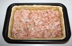 Подпеченную основу пирога засыпаем нарезанной небольшими кусочками красной рыбой, немного солим и перчим.