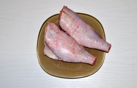 Кухонными ножницами срезаем плавники рыбы, соскребаем чешую, промываем (черная пленка внутри брюшка удаляется с помощью салфеток и острого ножа). Промокаем от воды бумажным полотенцем, делим каждую тушку на 3-4 куска.