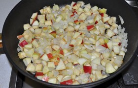 Хорошо разогреваем на среднем огне сковороду с 2-3 ст. ложками масла, 8-9 минут  пассеруем  лук, еще минуту – добавив в него раздавленные плоскостью ножа чесночинки. Засыпаем яблоки, перемешиваем,
