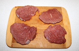 Делим говядину на 4 отбивные по 20-22 мм толщины (поперек волокон мяса). И несильными ударами молотка  отбиваем  обе стороны, делая их тоньше почти вдвое. Обязательно кончиком ножа рассекаем имеющиеся жилки, чтобы они не «стянули» мясо во время жарки. 
 
 
 