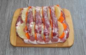 Крупную морковь очищаем и нарезаем тонкими кружочками (удобно – на терке для капусты). Закладываем в разрезы на грудинке. Кольца ананаса делим пополам и тоже вкладываем в разрезы. Если ананас кусочками – кладем по несколько штук.