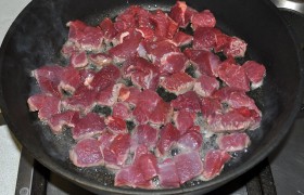 Вымытое мясо обсушиваем бумажным полотенцем. Нарезаем на ломти поперек волокон и затем – на среднего размера кусочки.    Раскаляем  сковороду с 2-3 ложками растительного масла и на этом огне обжариваем, помешивая, кусочки говядины до легкой корочки.