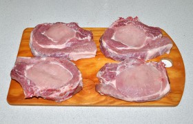 Выбранный кусок свиной корейки нам разрубили при покупке. Получились куски 30-35 мм толщины. Такие натуральные котлеты продают и уже нарезанные. Промываем, бумажными полотенцами промокаем, обсушиваем. Кожу и лишнее сало срезаем.