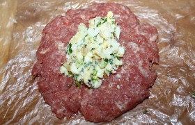 Формуем из фарша круглые лепешки толщиной 1 см. Удобно делать это на пищевой пленке, чтобы не прилипали. В центр лепешки выкладываем начинку.