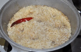 Пробуем рис. Он должен быть полуготовым и не хрустеть, если нет  - льем еще 50 мл кипятка и ждем, пока выкипит. Ножом делаем в рисе несколько отверстий до дна и еще убавляем огонь.