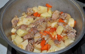 Чистим и нарезаем картошку, добавляем к мясу с заправкой, солим, можем еще посыпать душистой приправой типа  Прованских тра в. Доливаем еще воды – не больше стакана. 