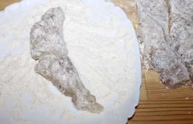 Пока на сковороде  перекаливается  растительное масло, тщательно  панируем  (обваливаем) ломти рыбы в муке, стряхивая лишнюю.