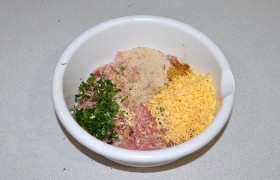 Проворачиваем мясо в мясорубке. В эту же миску мелко трем сыр, засыпаем панировочные сухари, приправу, измельченный чеснок, перец и соль, рубленую зелень. Руками вымешиваем фарш не менее 2-3 минут, несколько раз  отбиваем .