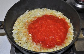 Помидоры из банки мелко рубим, выливаем в сковороду, посыпаем орегано, слегка солим и перчим. 
