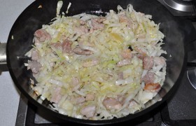 Свинина стала светлой и начинает браться корочками – всыпаем капусту и продолжаем жарить с мясом примерно 3 минуты.