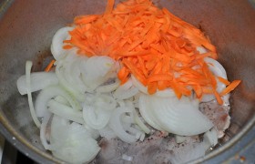 Добавляем весь, нарезанный полукольцами, лук и большую горсть крупно тертой или нашинкованной соломкой моркови, снижаем огонь до средне-сильного и обжариваем, пока лук станет румяным, а морковь помягчеет и даст вкусный запах.