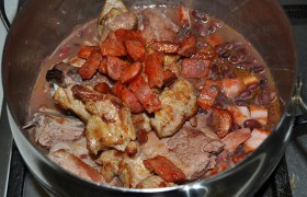 Колбасу и мясо тоже загружаем в кастрюлю, накрываем, регулируем огонь, который должен обеспечивать слабое кипение, и блюдо тушится 30-35 минут.