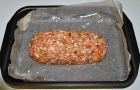 Запекаем мясной хлеб, либо помещая фарш в подходящую форму, либо на противне (в большой форме). Так как в небольшой высокой форме мы уже  готовили  – сегодня пробуем на противне. Формуем из фарша батон и выкладываем на дно, застеленное пекарской бумагой, промазанной маслом.