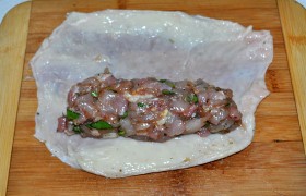 Куриную кожу промываем, досуха промокаем бумажными полотенцами, жир с нее не снимаем – мясо будет сочнее. Кладем порцию начинки – не слишком много, чтобы было удобно заворачивать.
