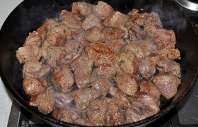 Толстодонную просторную сковороду, в которой мясо помещается в один ряд, с парой ложек масла  раскаляем  на сильном огне. Выкладываем кусочки, разравниваем, не трогаем пару минут, пока они поджариваются с нижней стороны. 