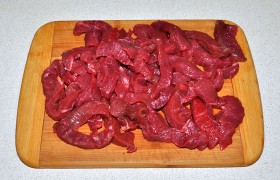 Хорошо промытый кусок мяса избавляем от лишней жидкости с помощью сложенных бумажных полотенец. Чем лучше мы подсушим говядину, тем качественнее и быстрее сможем пожарить ее. Нарезаем тонкими, не толще 15 мм, брусочками. Посыпаем перцем.