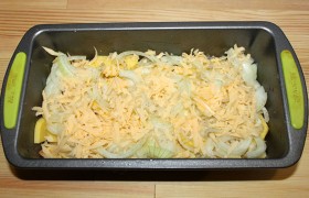 Чистим картофель, нарезая его тонкими ломтиками. Смазываем подходящую форму (у нас – 24х13, высота стенок – 7 см) маслом. Засыпаем на  дно примерно половину картофельных ломтиков, сдабриваем солью-перцем, покрываем полукольцами лука, тертым сыром.