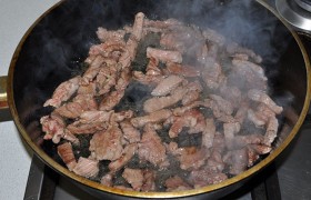 В сковороде на сильном огне  перекаливаем масло  до дымка. Мясо выкладываем столько, чтобы легло свободно в 1 ряд. Обжариваем, перемешивая, не больше 2 минут. Когда говядина становится светлой, а сок из нее еще только начал выделяться - выкладываем в мисочку, накрываем. 