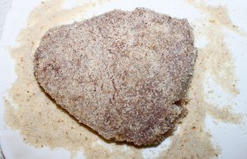 Поставив  перекаливаться  на сильный огонь сковороду с растительным маслом (слоем 6-8 мм), панируем мясо в  сухарях .