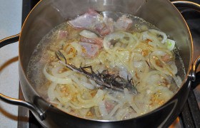 Выкладываем на мясо лук, тимьян, заливаем кипящей водой в уровень с мясом. На газовую конфорку ставим под казан рассекатель. Дождавшись закипания, накрываем крышкой и ставим на минимальный огонь, при котором мясо кипит практически незаметно. Тушим не менее 3 часов.