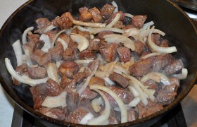 Засыпаем шинкованный полукольцами лук, всё также перемешивая, обжариваем еще 2-3 минуты.