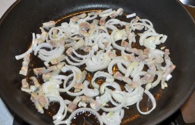 На сухой сковородке, на конфорке со средне-сильным огнем, слегка обжариваем бекон, добавляем полукольцами нашинкованный лук и помешиваем 2-3 минуты. Убираем на тарелку.