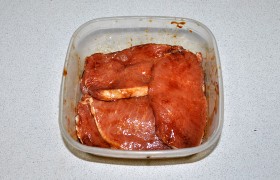 Надрезаем тонкий слой сала на стейках, чтобы он не стянул мясо при жарке.  Складываем ломти мяса, поливаем соусом, перчим, хорошо перемешиваем.