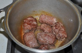 В казане (латке)  перекаливаем  на сильном огне растительное масло (до дымка). Кладем мясо, поворачивая на разные стороны, все их обжариваем до корочки. 