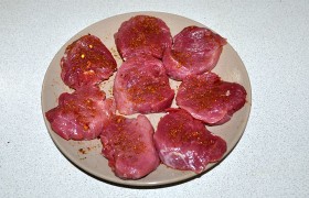 Слегка смазываем медальоны растительным маслом и посыпаем (или смазываем) аджикой, но осторожно, аджика - острая приправа. (Если готовить будем позже – накрываем пленкой и ставим на полку холодильника. Вынимаем мясо заранее, чтобы успело согреться.)