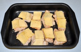 Шницели раскладываем в форме, предварительно промазанной маслом, солим, перчим. Сверху кладем ломтики сыра. 