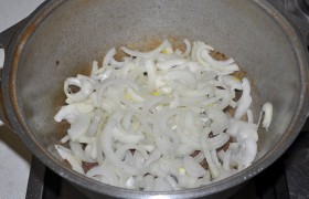 Теперь мясо солим и перчим, перемешиваем, засыпаем слой шинкованного полукольцами лука.