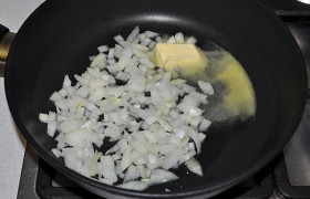 Луковицу очищаем, нарезаем мелко и высыпаем в разогретую средним огнем сковороду, где тает сливочное масло. 7-10 минут помешиваем лук, пока он пассеруется до мягкости.