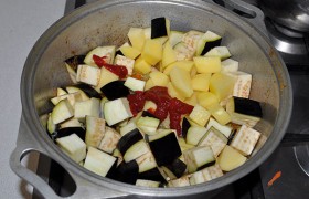 Закладываем кубики картофеля и баклажана. Приправляем томатной пастой. Наливаем немного воды, полстакана-стакан.