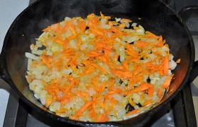 Для заправки супа мелко шинкуем лук, засыпаем в сковороду, где разогрели масло. На среднем огне пассеруем, помешивая, 5-6 минут. Добавляем морковку и помешиваем овощи еще 3-4 минуты.
