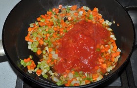 Дольки чеснока помещаем в пресс, выжимаем над сковородой, перемешиваем. Через минуту заливаем раздавленные вилкой томаты. Тушим 3-4 минуты.