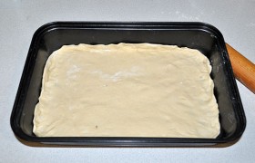 Выкладываем тесто в форму, смазанную маслом, приподнимая края пласта.