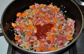 А в сковороду кладем нарезанные мясопродукты, через 3-4 минуты - томатную пасту, добавляем сахар, немного кипятка, тушим 2-3 минуты.