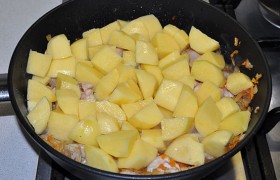 Кладем в сковороду очищенную нарезанную картошку, приправляем, наливаем немного воды. Накрываем, ставим небольшой огонь, на котором блюдо тушится до готовности картофеля и мяса, 15-20 минут.