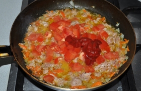 Помидор разрезаем и натираем на терке, кладем в заправку вместе с томатной пастой, добавляем 1-2 половника кипятка из суповой кастрюли, тушим 2-3 минуты.