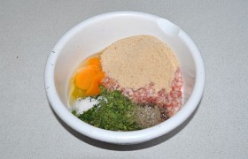 В миску с мясным фаршем добавляем сухари, яйцо, соль и перец, немного рубленой мелко зелени. 
