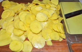 Ставим кипятить чайник, а пока чистим картофелины, выбрав те, что помельче, чтобы ломтики были небольшими. Нарезаем их очень тонко, для чего используем терку для капусты.