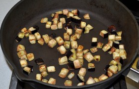 Параллельно во второй сковороде готовим баклажан. Нарезаем кубиками и высыпаем в сухую разогретую сковороду, помешивая, подпекаем до корочек, убираем из сковороды.