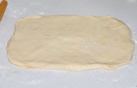Сливочное масло ставим растапливаться, в это время раскатываем тесто тремя одинаковыми прямоугольниками. Каждый щедро смазываем маслом и складываем друг на друга.