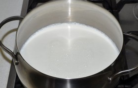 Заливаем молоко в кастрюлю, ставим на средний огонь. В кружку наливаем отмеренное количество кефира. Вскоре на поверхности начинают появляться пузыри.