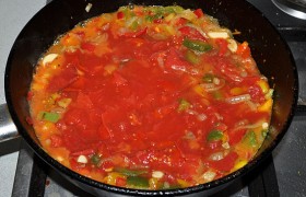 Консервированные помидоры измельчаем, вливаем вместе с соком в сковороду. Помешивая, даем закипеть, приправляем по вкусу солью и перцем, сахаром, который делает соус менее кислым.