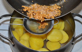 Сливаем чесночное масло через ситечко в кастрюлю с картошкой. 