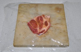 Посыпаем мясо приправами и солью, накрываем полиэтиленовой пленкой и отбиваем с обеих сторон, 