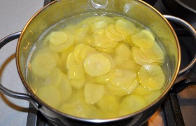 Складываем ломтики в кастрюлю и заливаем – чуть-чуть выше картофеля – кипящей водой. Перемешиваем, солим, варим 4-6 минут – за это время картошка практически полностью готова. 
